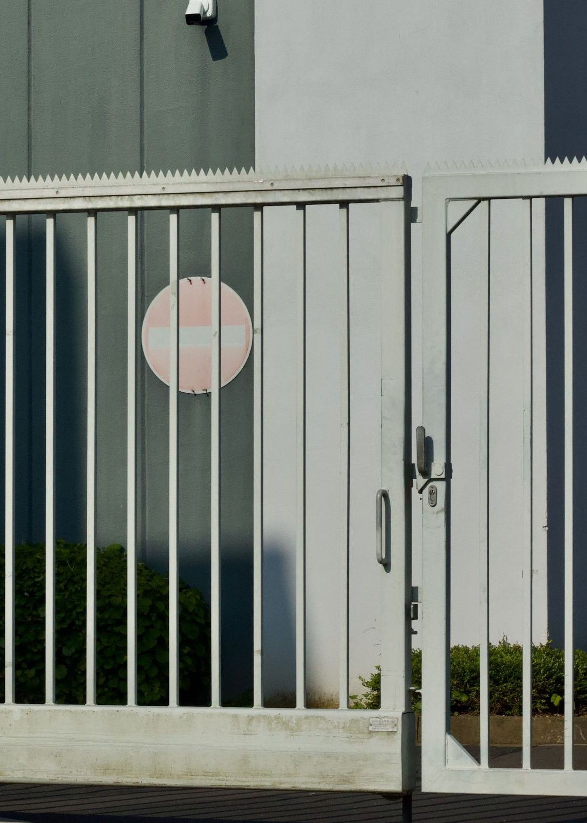 Photo of a secured industrial building with a white metal gate, under clear blue sky.