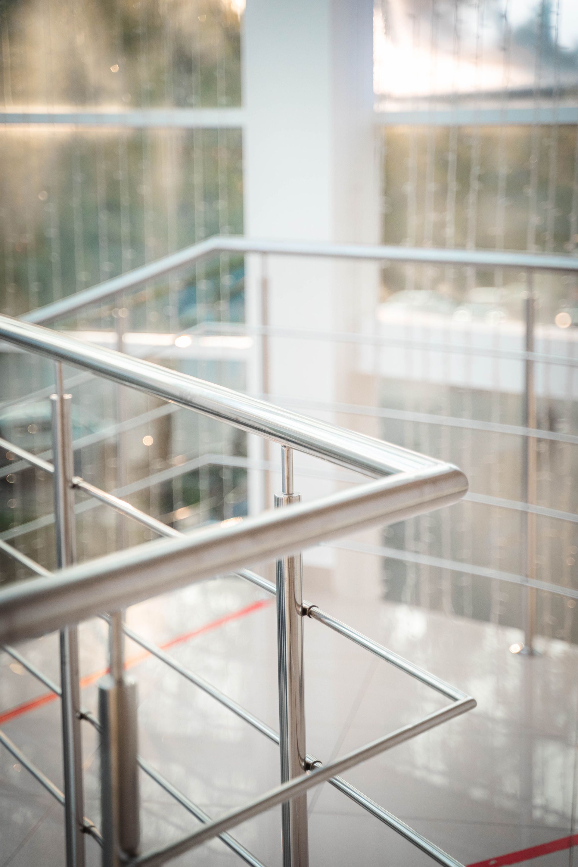 A close-up view of a stainless steel staircase railing in a sunlit indoor setting, highlighting modern design.