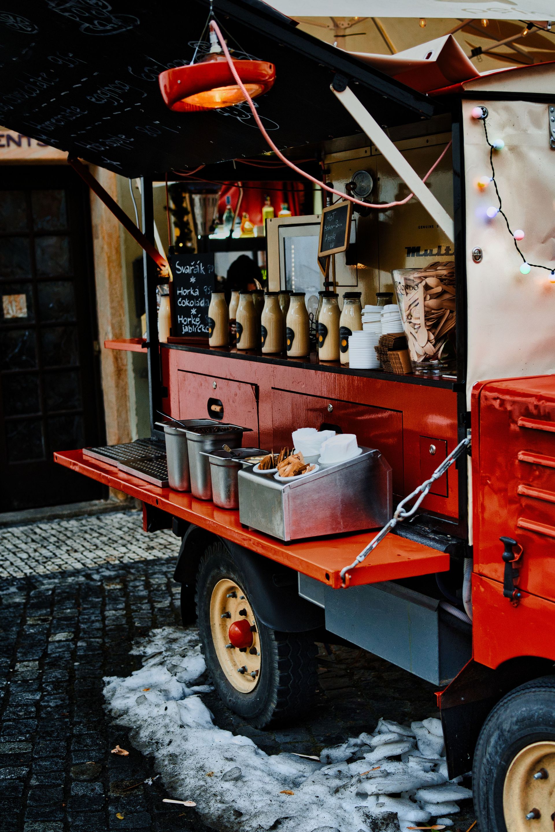 Vibrant red food truck offering street food in an urban winter setting.